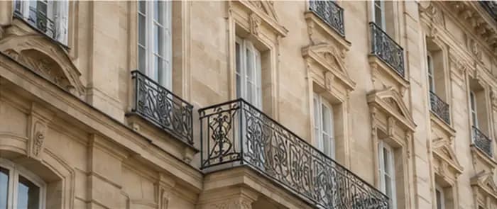 Immobilier et patrimoine — architecture et durée Façade en pierre claire avec balcons en ferronnerie.